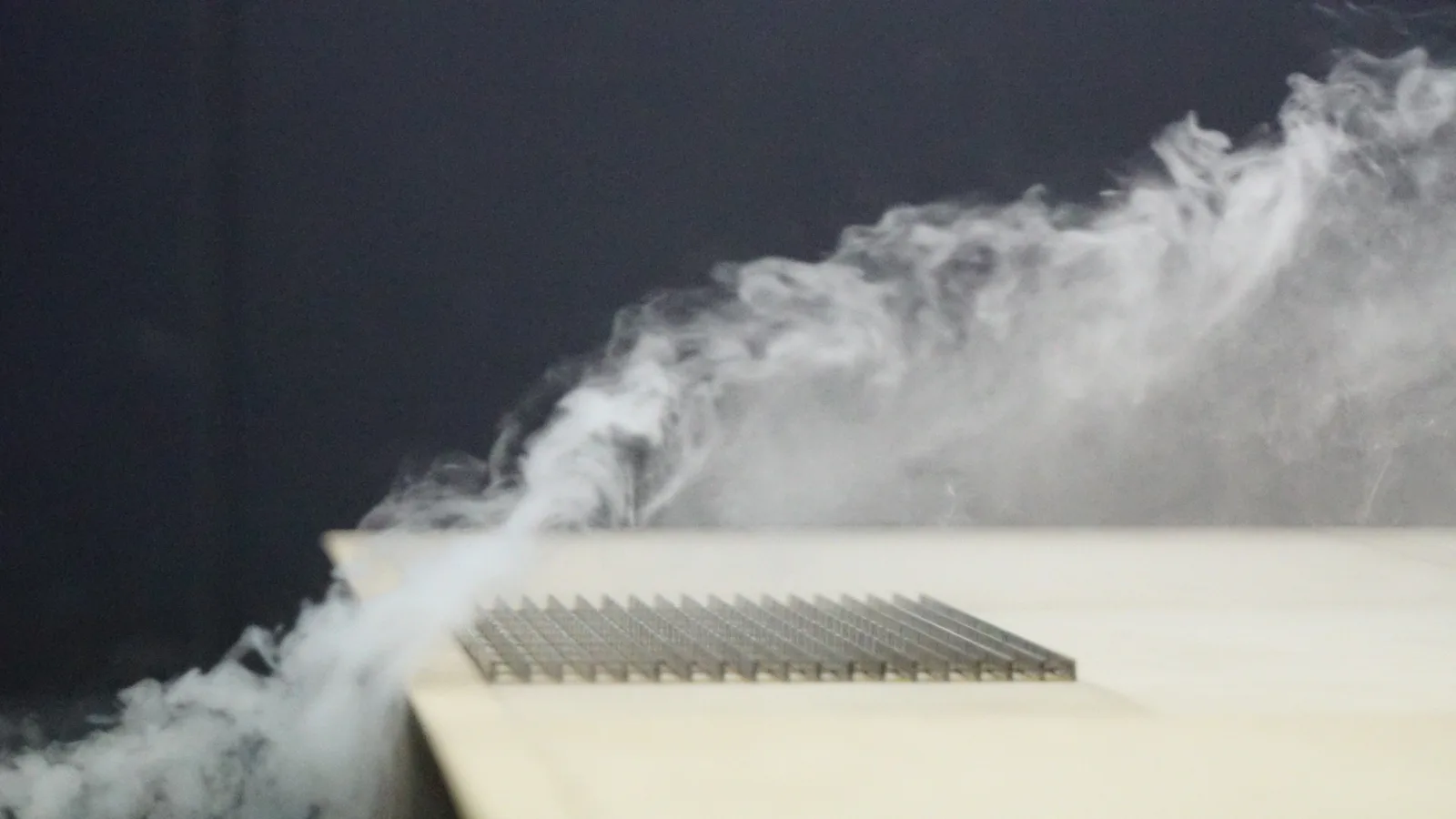 Vertical solar panel in a wind tunnel with airflow visualised by smoke