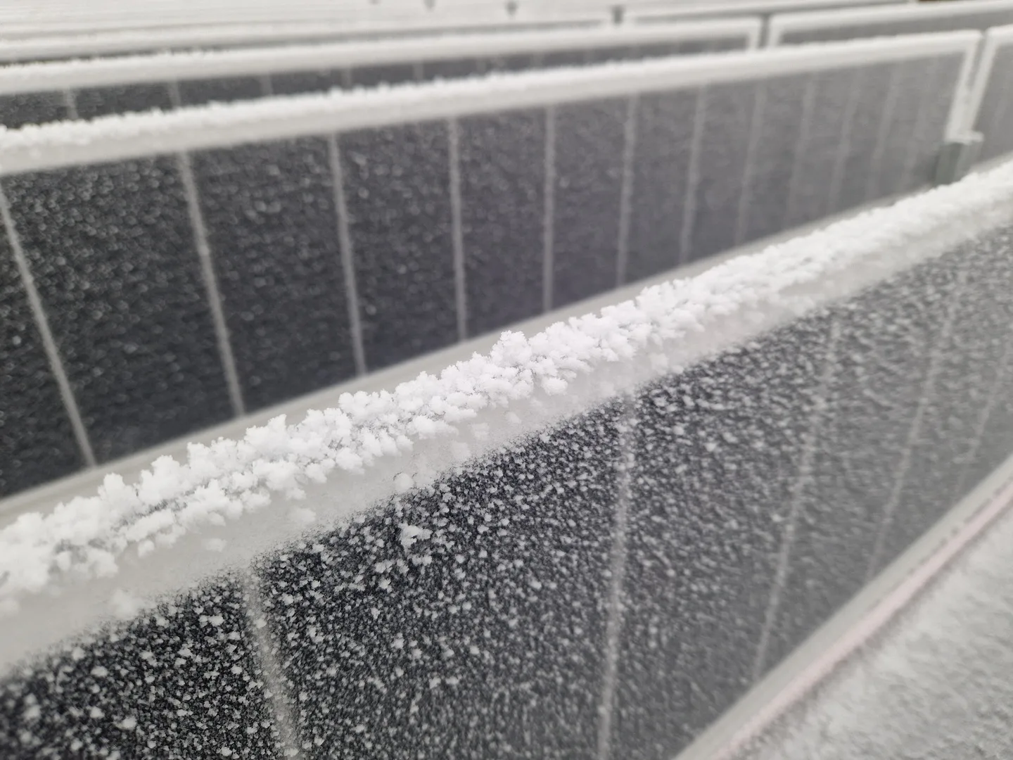Vertical solar units covered in ice and snow during a storm in Tromsø